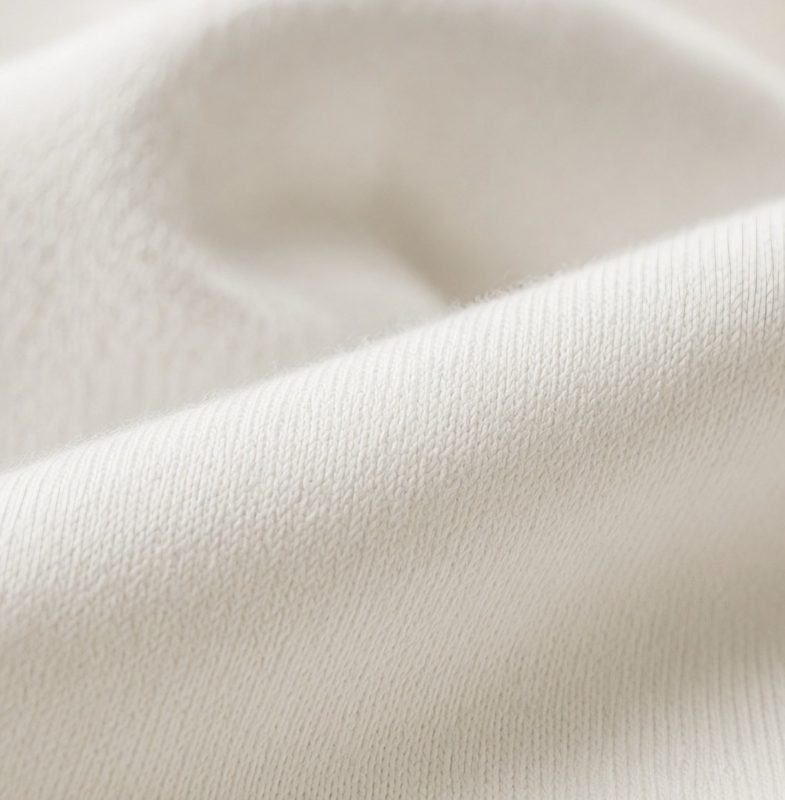 Macro view of soft white organic cotton jersey, gently draped.